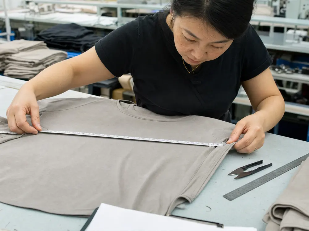 Quality control specialist measures a finished garment and checks stitching against specifications